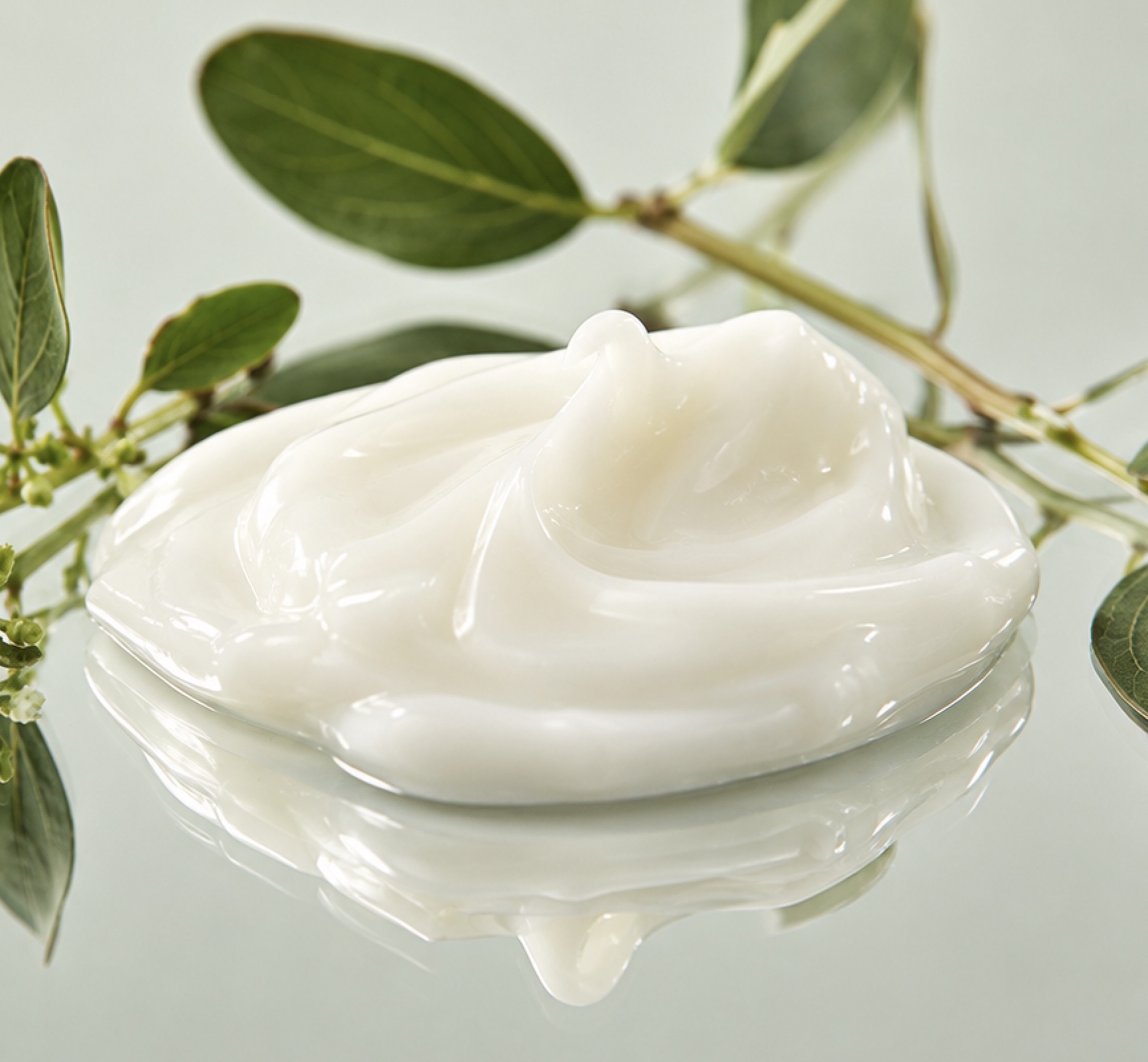 Swirl of white conditioning cream beside green leaves