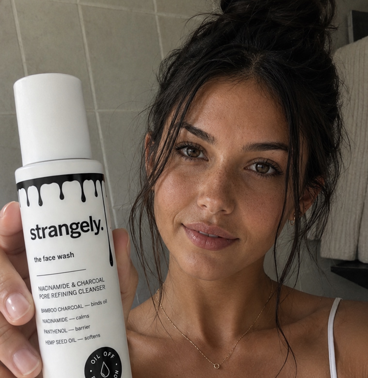 Model holding the strangely. Niacinamide & Charcoal Cleanser bottle