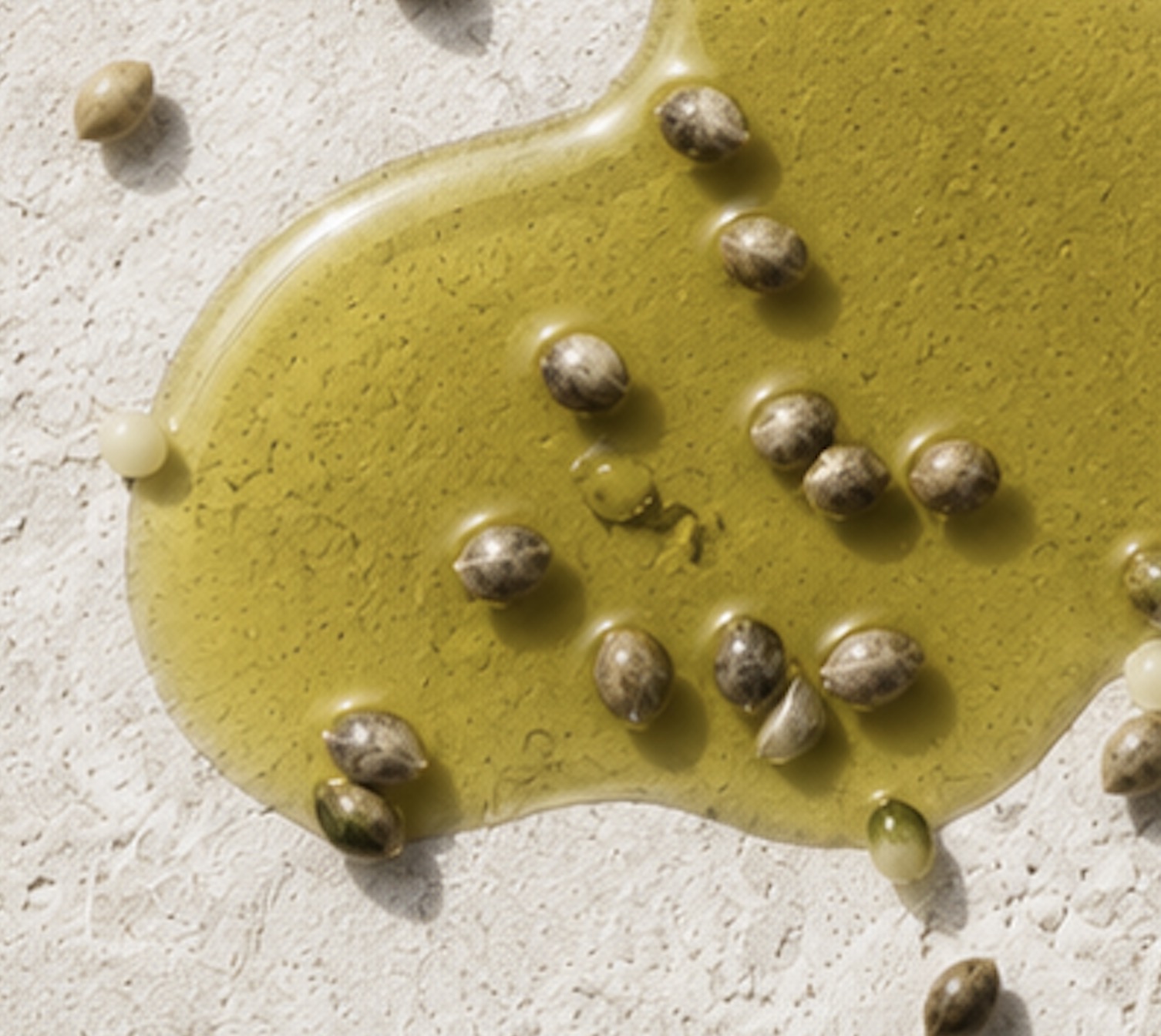 Green hemp seed oil with hemp seeds on a pale textured surface