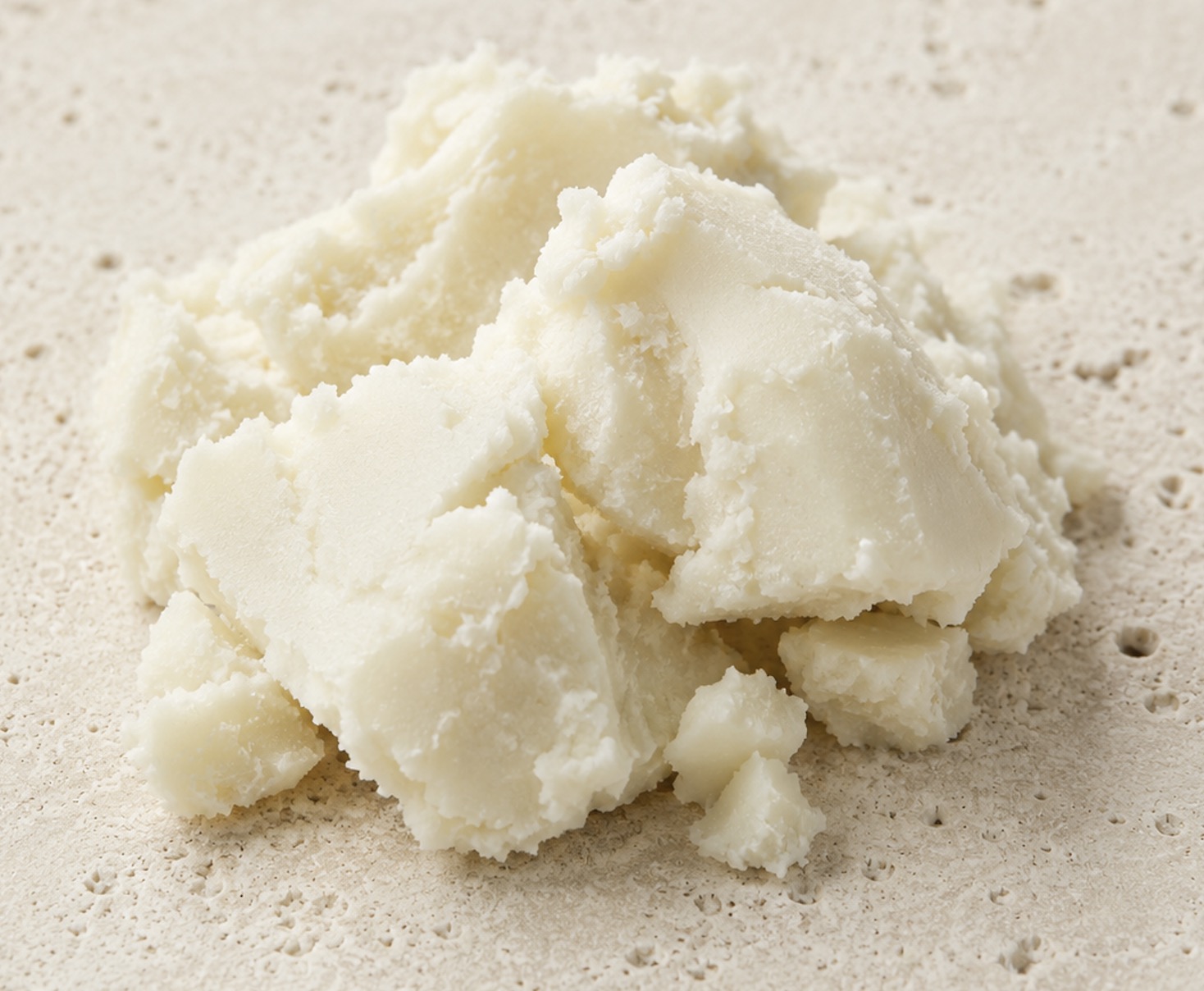 Scooped chunks of raw ivory shea butter on stone