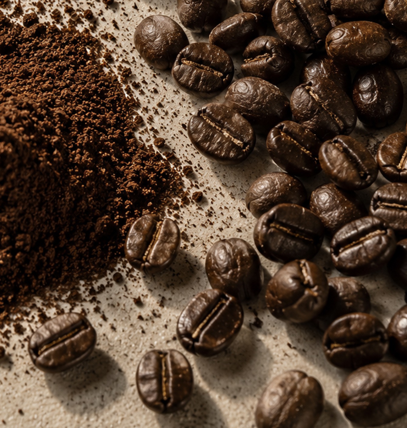 Roasted coffee beans beside a heap of fresh ground coffee