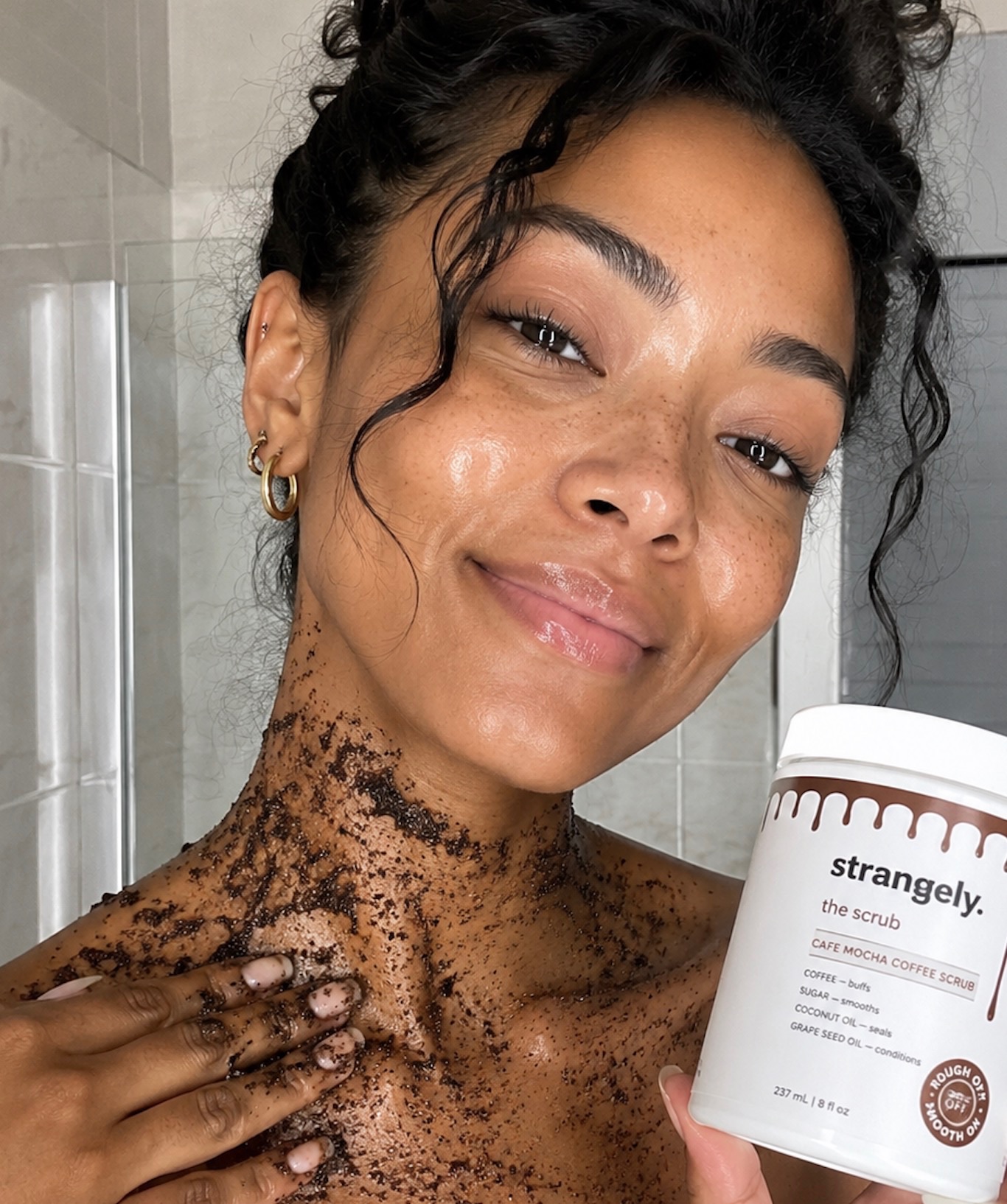 Coffee scrub applied on shoulders and chest in the shower, jar in hand